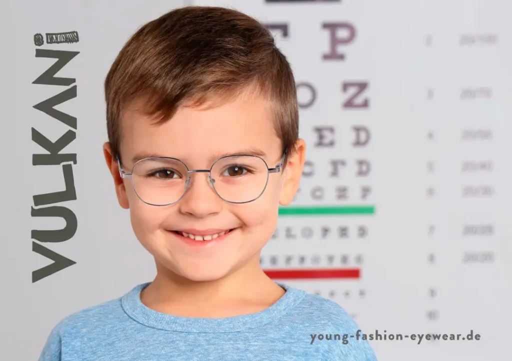 Ein kleiner Junge, der eine dünne Metallbrille trägt und lächelt.
