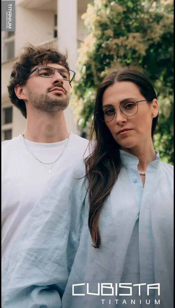 Ein junger Mann und eine junge Frau tragen beide ein weißes Oberteil und eine große Metallbrille.