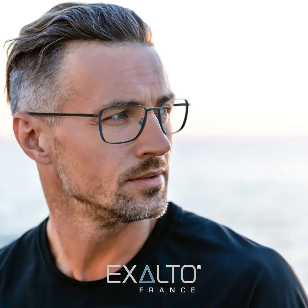 Mann mit kurzen dunklen Haaren, einem schwarzen T-Shirt und einer dunklen Metallbrille.