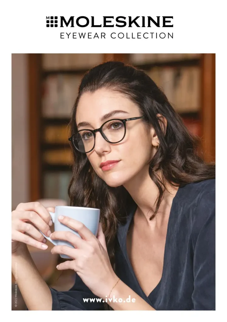 Junge Frau mit langen dunklen Haaren, einer schwarzen runden Kunststoffbrille und einer weißen Kaffeetasse