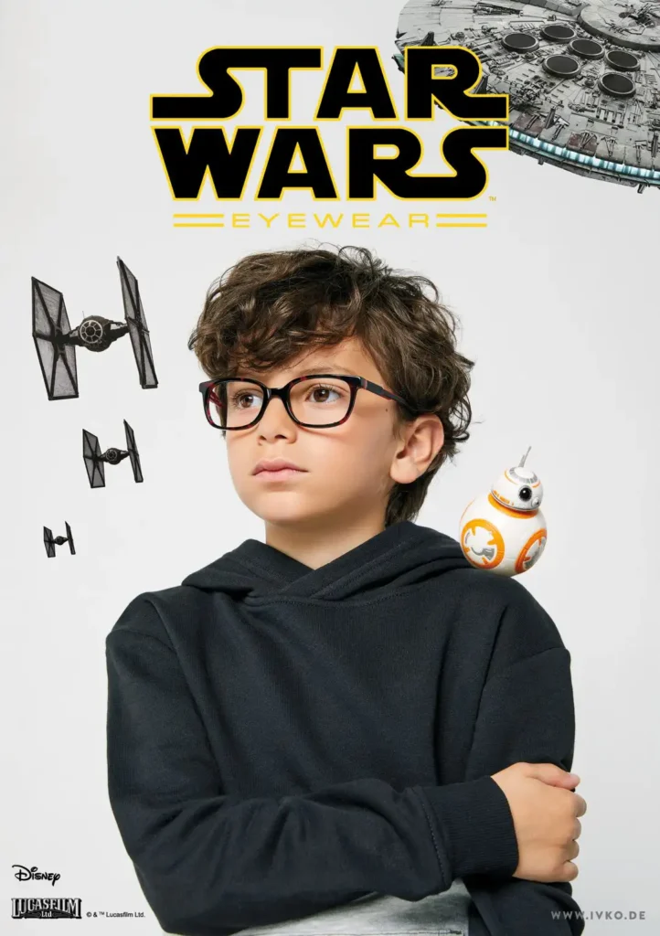Ein Junge mit lockigen dunklen Haaren in einem schwarzen Hoodie trägt eine schwarze Kunststoffbrille. Im Hintergrund sind Raumschiffe von Star Wars zu sehen.