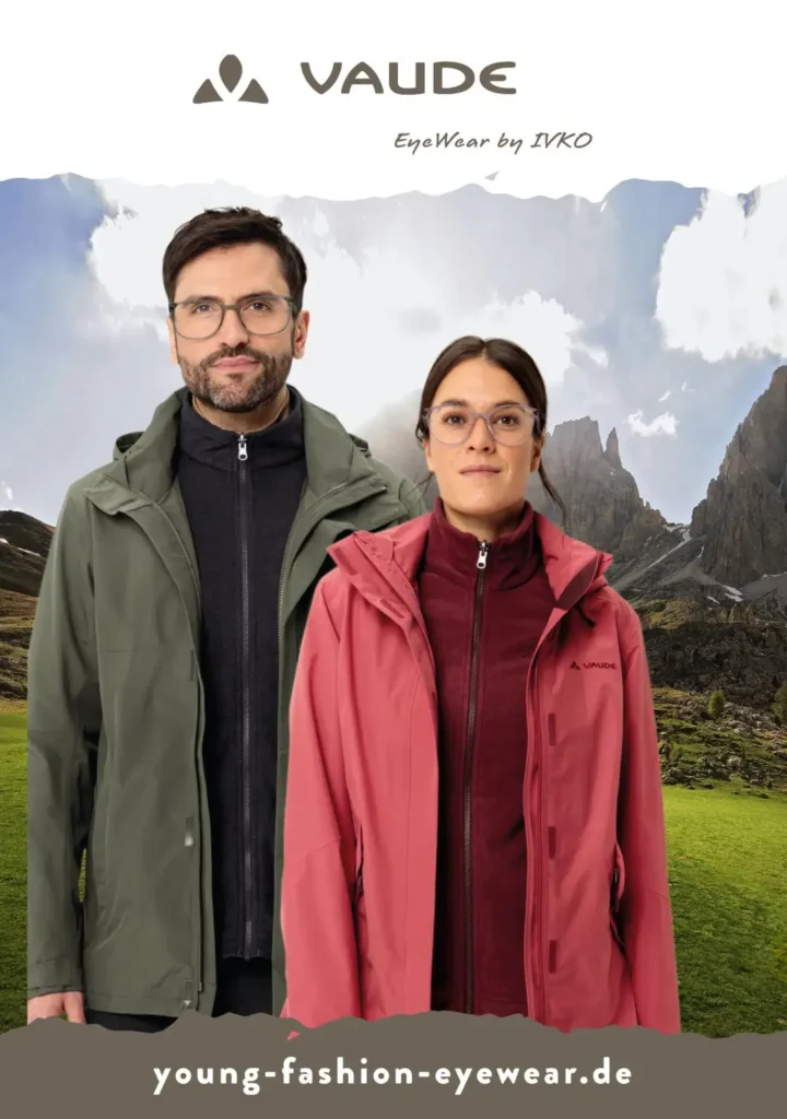 Ein Mann und eine Frau stehen in Outdoorbekleidung vor Bergen und tragen große Brillen.